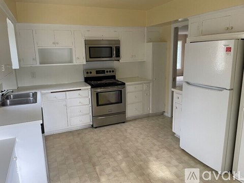 A kitchen with white cabinets and appliances.