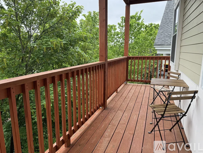 A wooden deck with chairs and a view of trees.