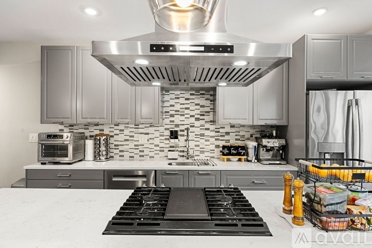 A modern kitchen with a stove top in the foreground.