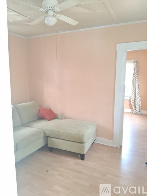 A living room with a light colored couch and a fan on the ceiling.
