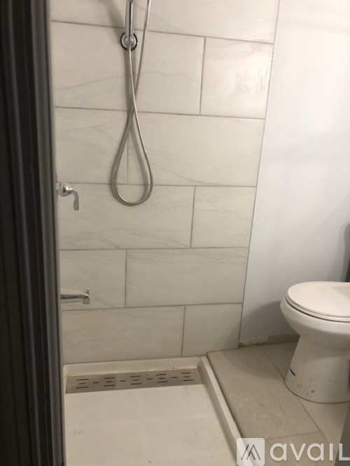 A white toilet in a bathroom with a shower head and a drain.