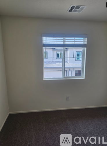 A room with a window showing a view of a building outside.