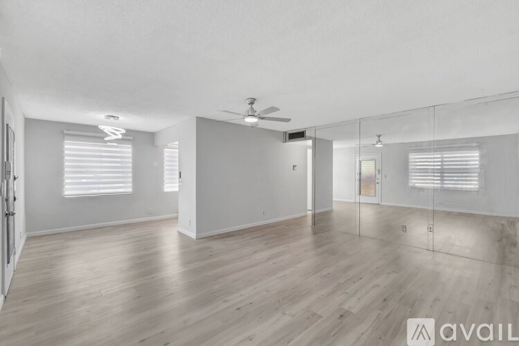A spacious room with wooden flooring and a ceiling fan.