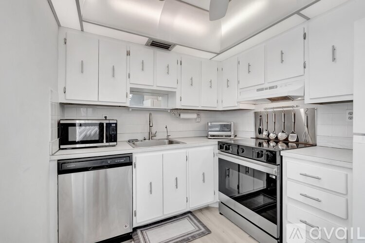 A modern kitchen with white cabinets and stainless steel appliances.
