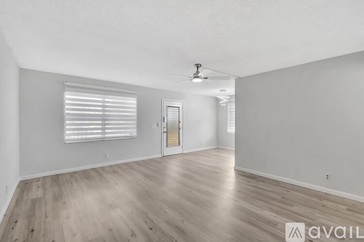 A spacious room with wooden flooring and a ceiling fan.
