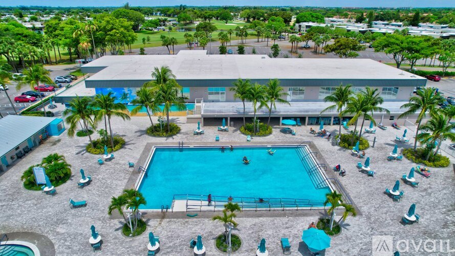 A large swimming pool surrounded by palm trees and lounge chairs.