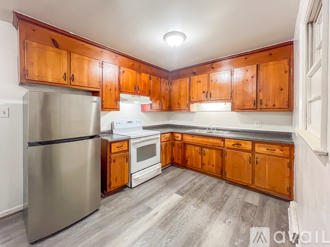 A kitchen with wooden cabinets and a stainless steel refrigerator.