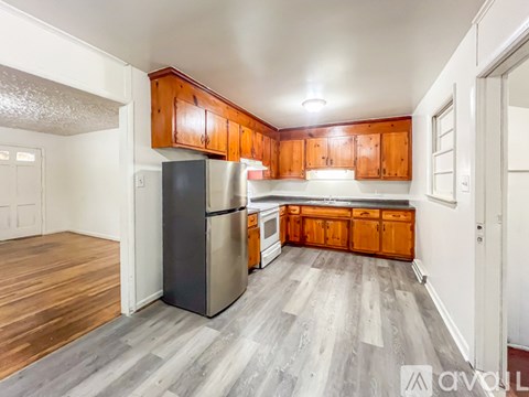 A kitchen with wooden cabinets and a black refrigerator.
