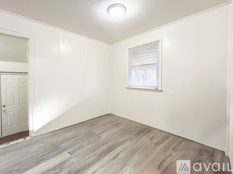 A room with a window and wooden flooring.