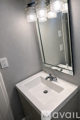 A white sink under a mirror with lights above it.