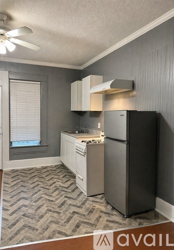 A kitchen with a black refrigerator, white cabinets, and a patterned floor.