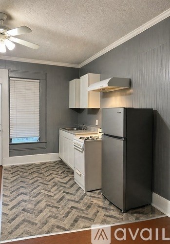 A kitchen with a black refrigerator, white cabinets, and a patterned floor.