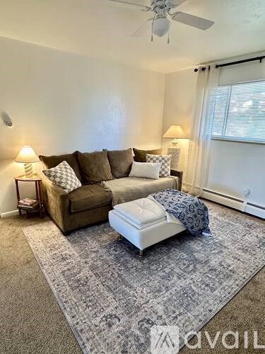 A living room with a brown couch and a white ottoman.