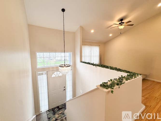 A room with a ceiling fan and a window with a view of trees.