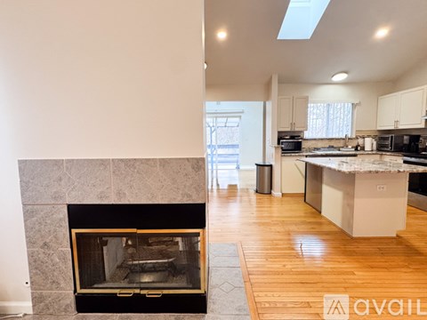 A modern kitchen with a fireplace and wooden floors.