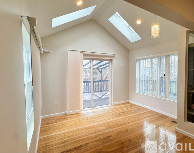 A spacious room with wooden floors and skylights.
