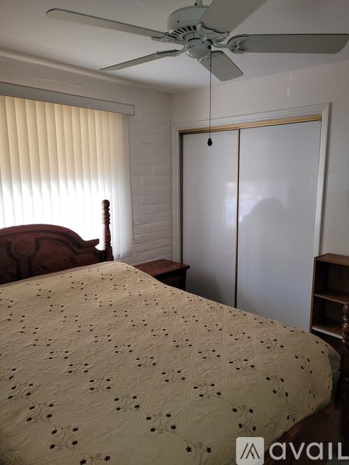 A bedroom with a bed, a ceiling fan, and a wardrobe.