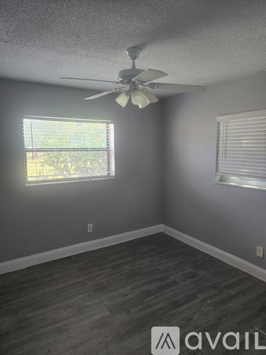A room with a ceiling fan and two windows.
