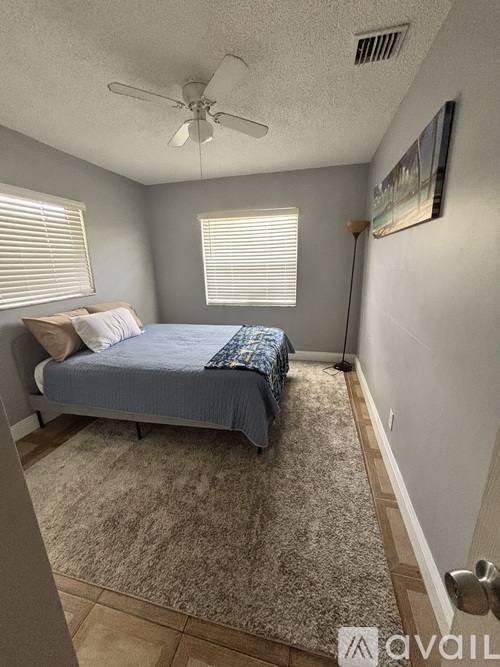 A bedroom with a bed, carpet, and a ceiling fan.