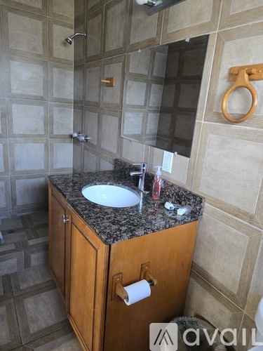A bathroom with a granite countertop and a wooden cabinet.