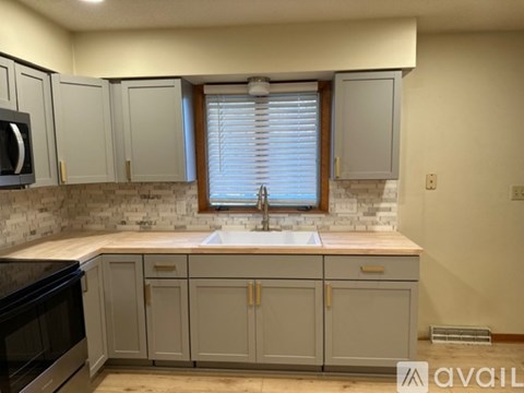 A kitchen with a sink, cabinets, and a microwave.
