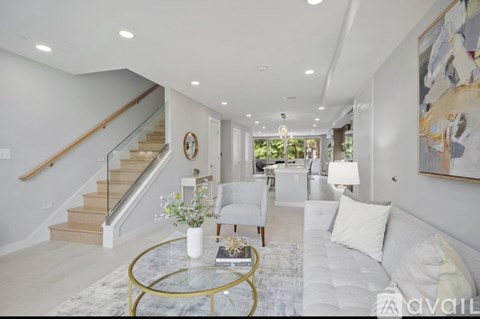 A living room with a glass coffee table and a staircase.