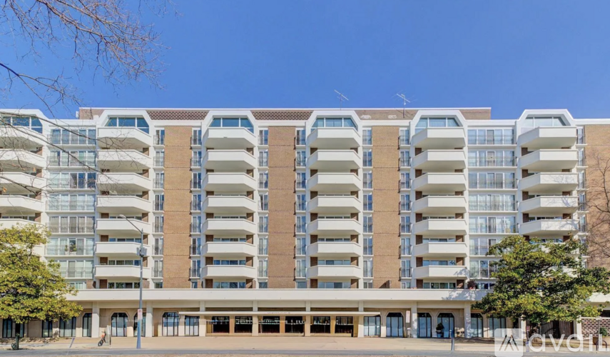 A large apartment building with multiple balconies and a clear blue sky above.
