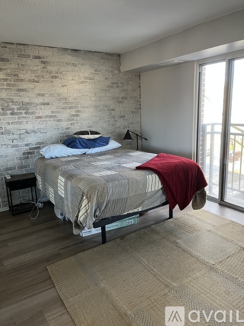 A bedroom with a bed, a chair, and a rug.