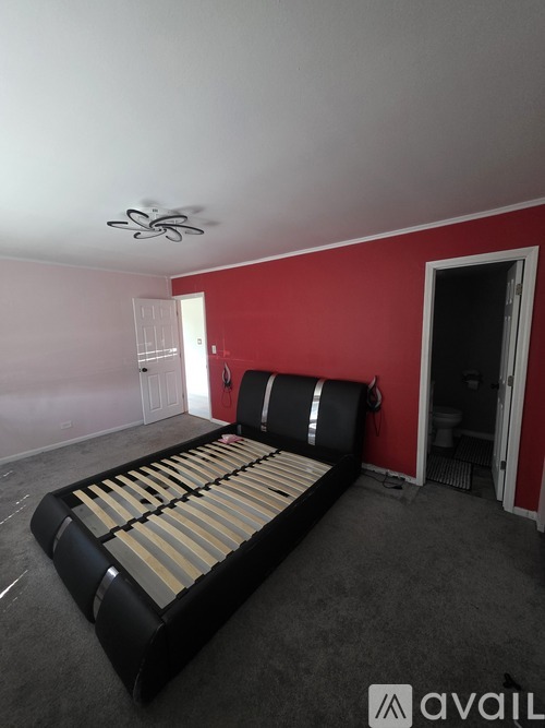 A bedroom with a bed, a ceiling fan, and a red wall.