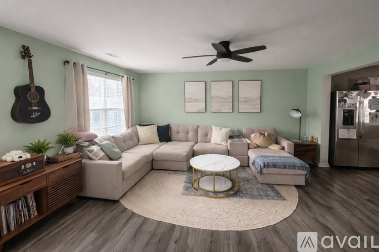 A living room with a large sectional sofa, a coffee table, and a guitar hanging on the wall.
