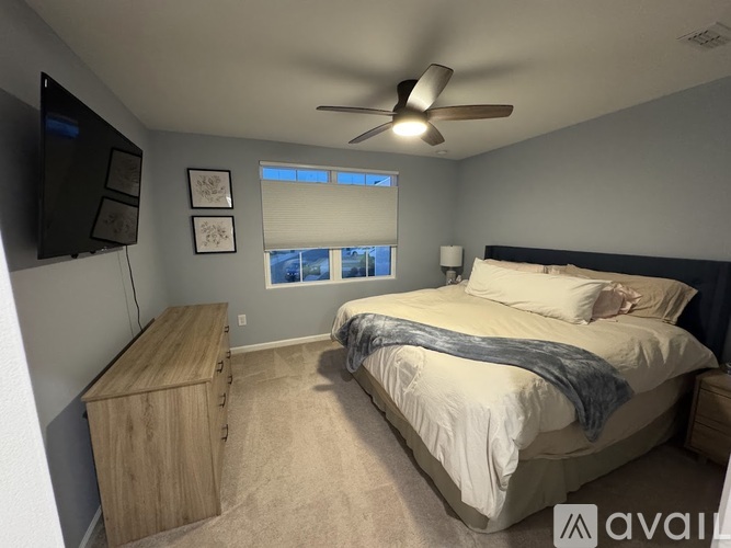 A bedroom with a bed, a ceiling fan, and a window with blinds.