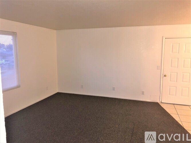 A room with a carpeted floor, a door, and a window.