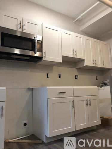 A kitchen with white cabinets and a microwave above the oven.