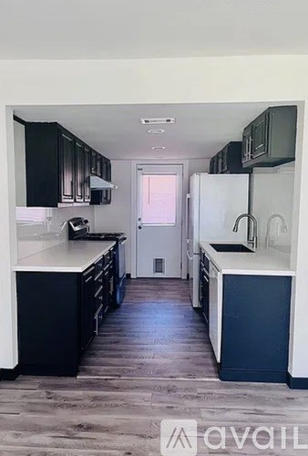 A kitchen with black cabinets and a white refrigerator.