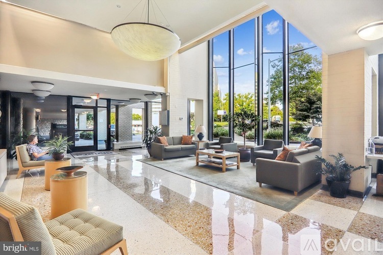 A spacious living room with a marble floor and a large window overlooking a garden.