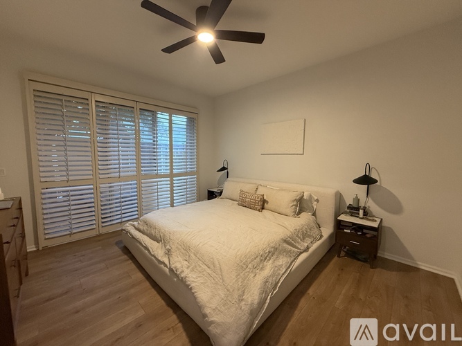 A bedroom with a bed, a nightstand, and a ceiling fan.