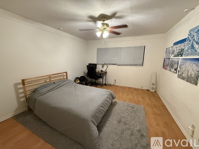 A bedroom with a bed, a ceiling fan, and a wall-mounted shelf with pictures.