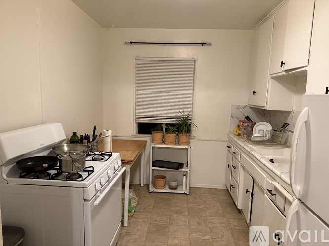 A small kitchen with a white stove and white cabinets.