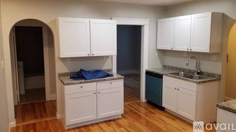 A kitchen with white cabinets and a granite countertop.
