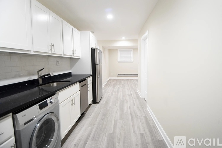 A kitchen with white cabinets and black countertops.