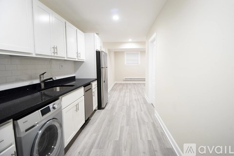 A kitchen with white cabinets and black countertops.