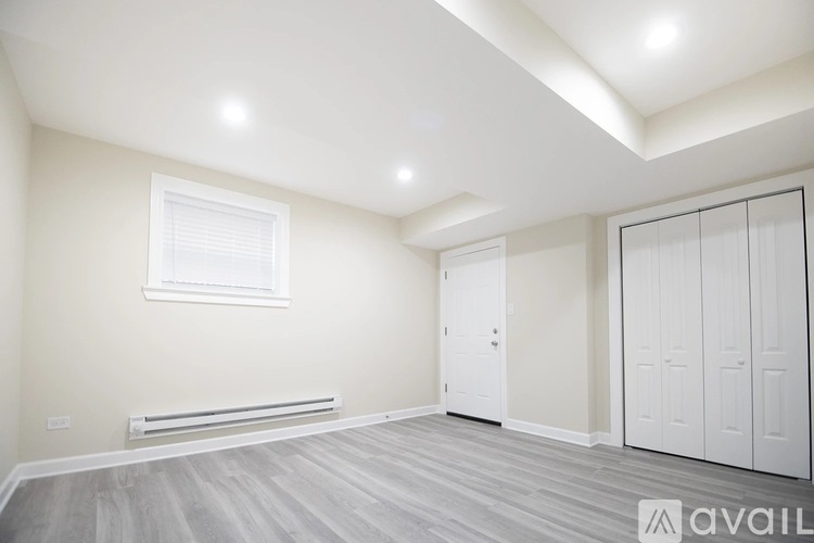 A spacious room with a window, a radiator, and a wooden floor.