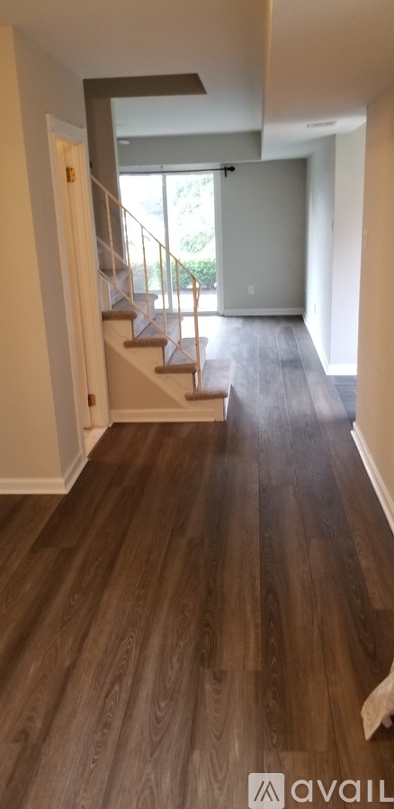 A hallway with wooden floors and a staircase.