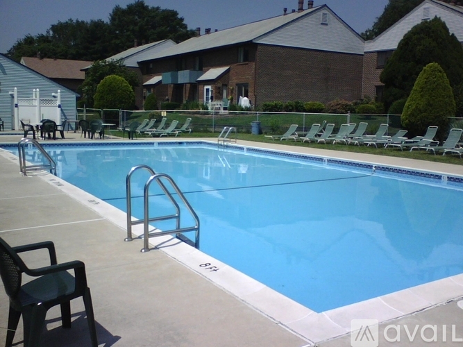 A pool with chairs around it and a house in the background.