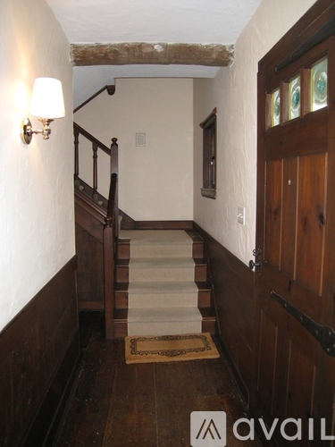 A hallway with a wooden door and stairs.