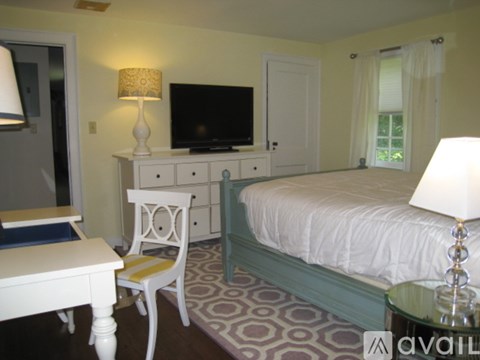 A bedroom with a bed, chair, and television.