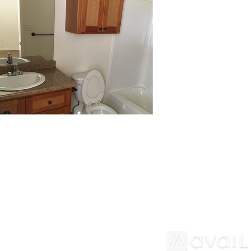A bathroom with a toilet, sink, and wooden cabinets.