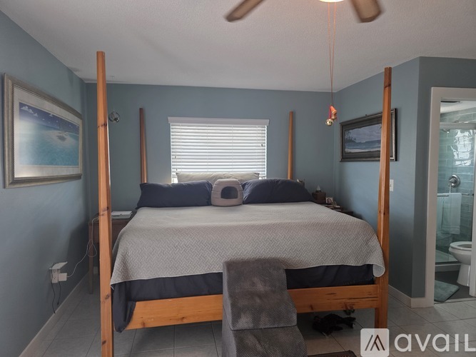 A bedroom with a four poster bed and a ceiling fan.
