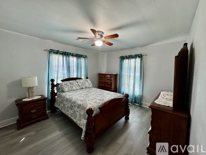 A bedroom with a bed, dresser, and ceiling fan.