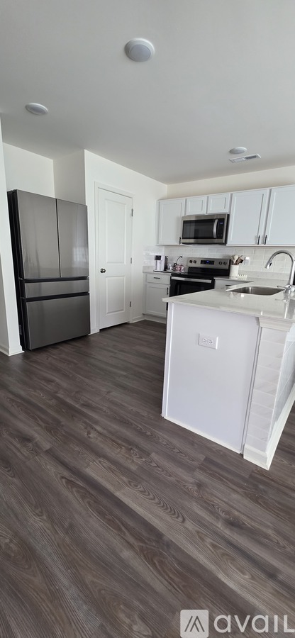 A kitchen with a white fridge and wooden floors.